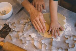 2 pairs of hands using cookie cutters on raw dough